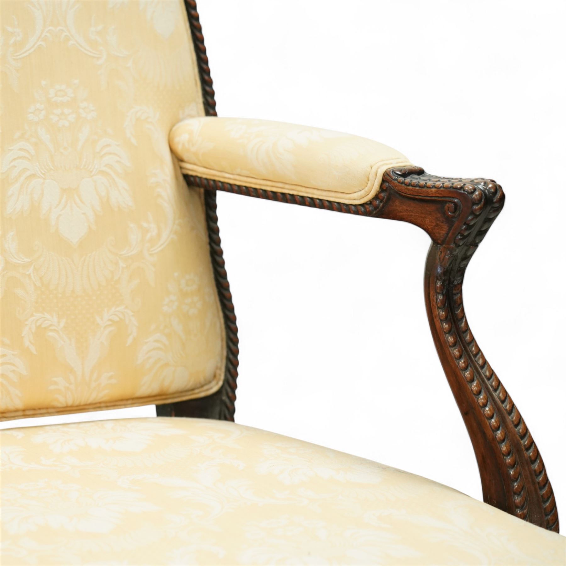 Early 20th century mahogany settee in the George III style, upholstered in pale yellow damask fabric, moulded serpentine seat rail with carved foliate detail, on cabriole supports with acanthus carved knees and scroll feet