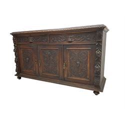 Victorian heavily carved oak sideboard, the moulded top carved with foliate decoration to the edge, fitted with two drawers and three cupboards, the drawer fronts carved with green man mask handles and scrolling foliage, the panelled doors carved with interlacing foliage, on turned compressed bun feet