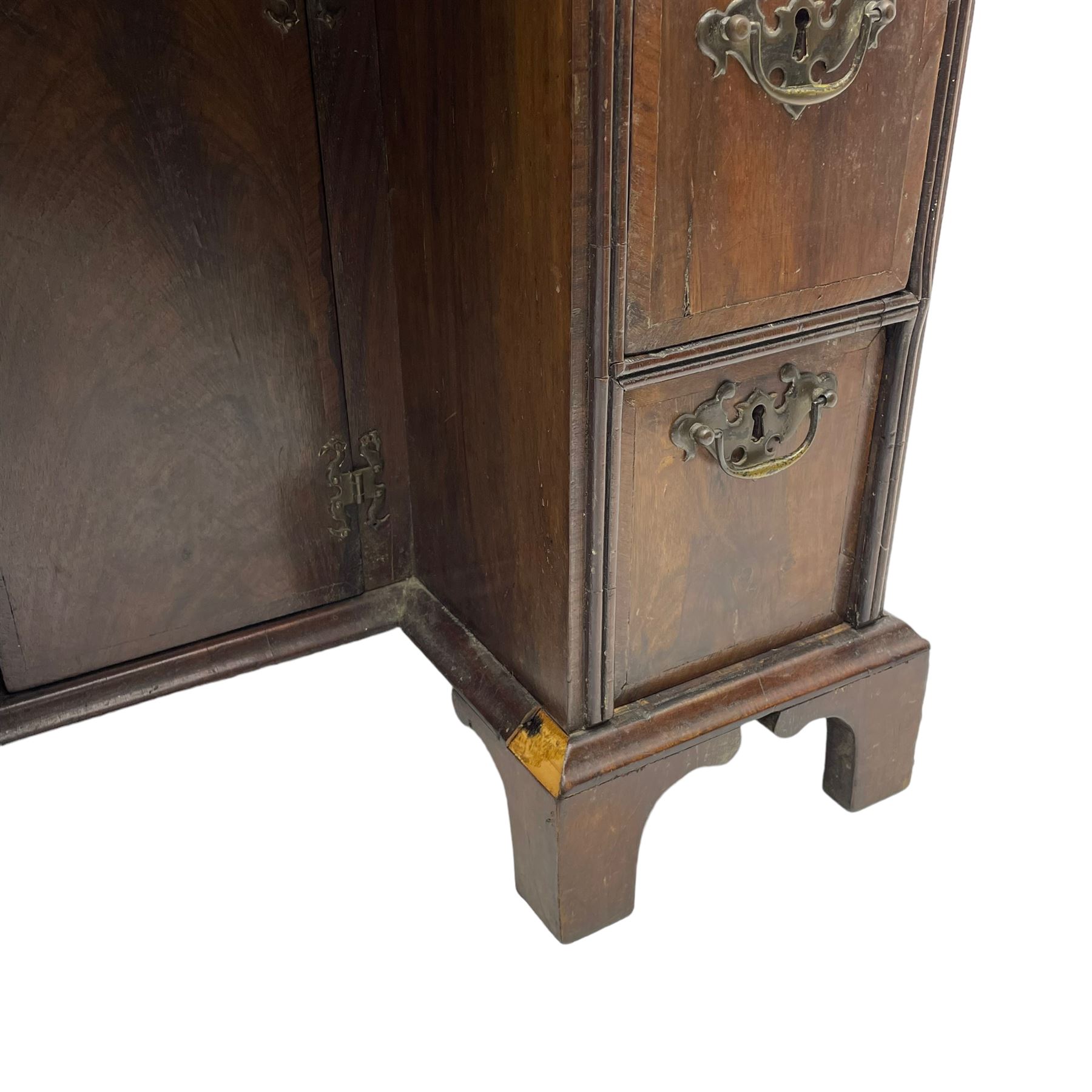 Georgian walnut kneehole desk, moulded rectangular top with book-matched veneers within crossbanding, fitted with slide over one long drawer, frieze drawer, six small drawers and recessed cupboard, raised on bracket feet