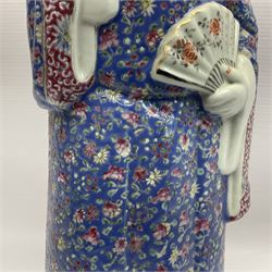 Chinese Republic Period porcelain figure, modelled as scholar holding a book and fan, wearing blue enamelled robes decorated with flower heads, H43cm