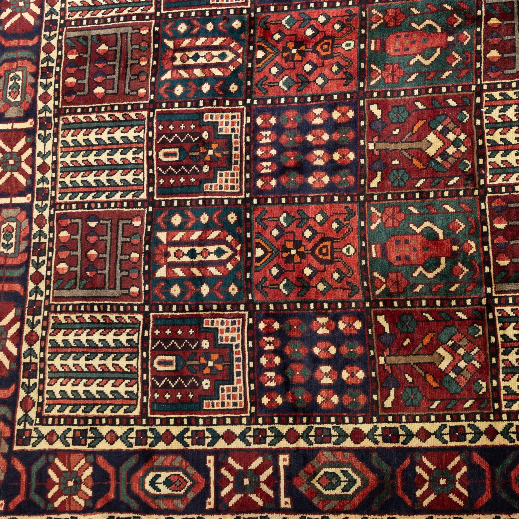 Bakhtiari wool rug, compartmented garden design field with panels of stylised trees, flowers and geometric motifs, enclosed by dark blue main border with repeating floral medallions and guard stripes
