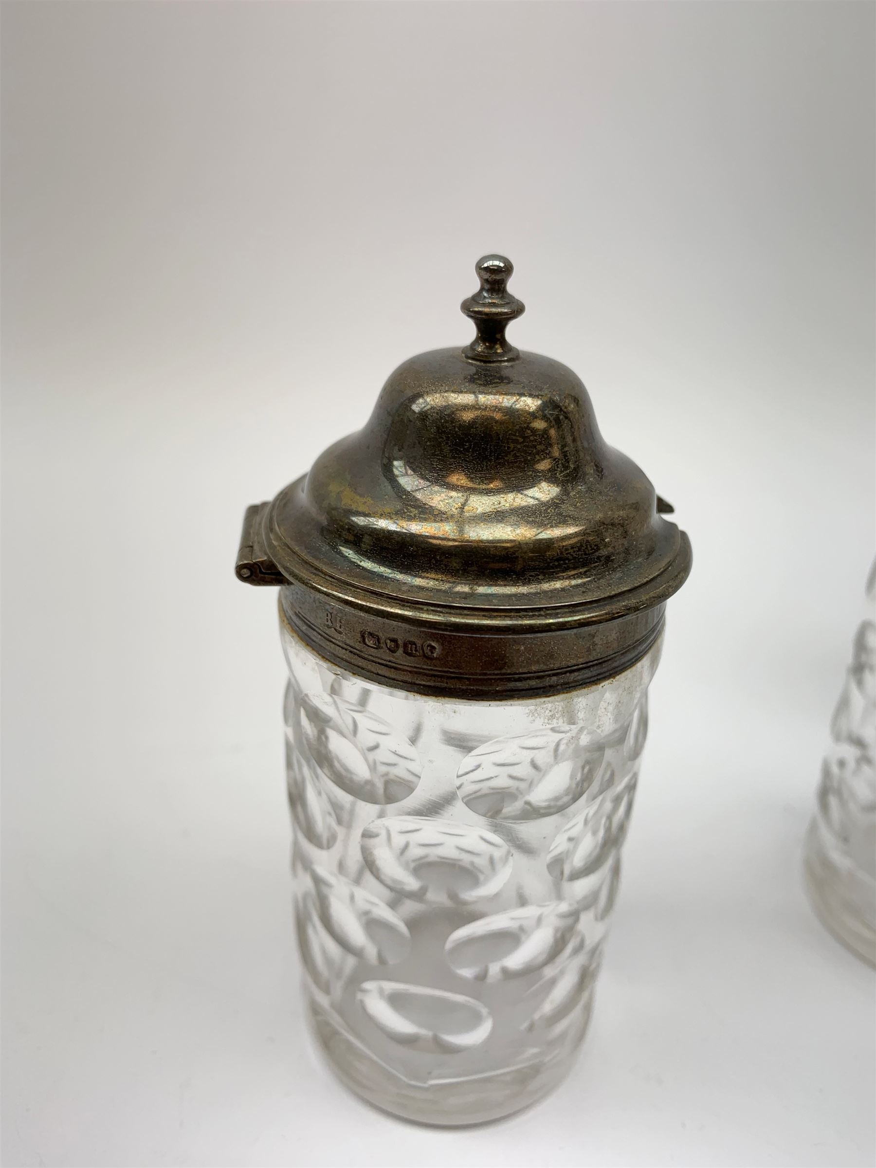 A group of Victorian glass condiment bottles, to include a set of four bottles and jar with cut decoration, one bottle with pierced silver domed top, another bottle with silver gilt spoon top, and jar with silver domed hinged cover, all hallmarked Robert Harper, London 1868. (8). 