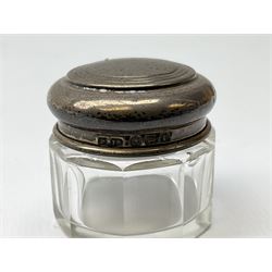 Hallmarked silver top dressing table jars, to include cut glass hobnail example with foliate engraved lid, another 20th century cut glass example with silver engraved screw thread lid, stamped H.S.M Herbert Scott Murdoch, with interior stopper and two smaller glass jars (4)