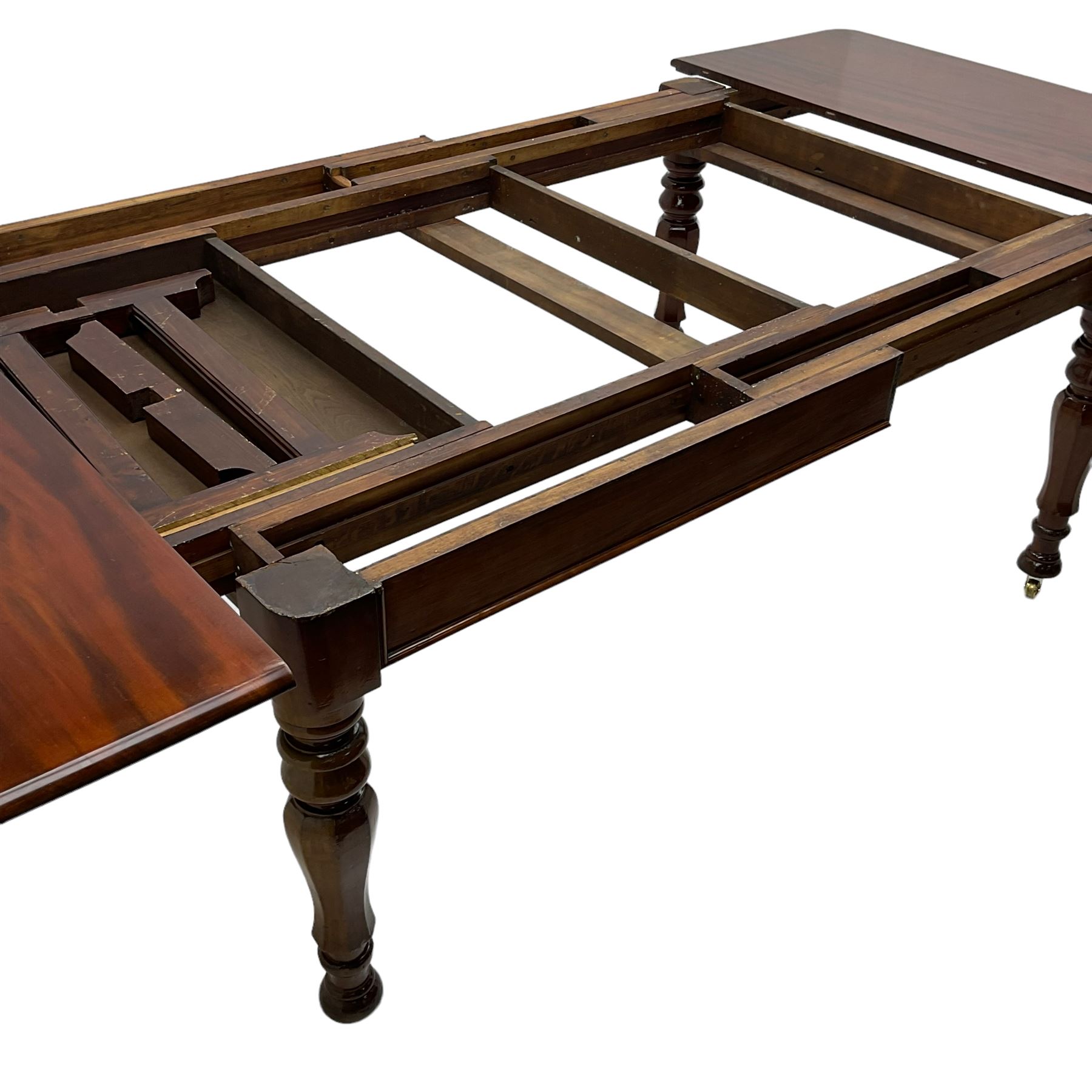 19th century mahogany extending dining table with three additional leaves, rectangular top with rounded corners, pull-out action, on turned and faceted supports with brass castors
