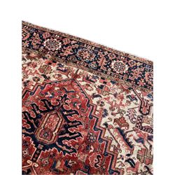 Persian Heriz red ground carpet, large stylised pole medallion surrounded by Pitrak motifs, indigo ground border decorated with stylised flower heads and trailing leafy branches, within floral pattern guard stripes