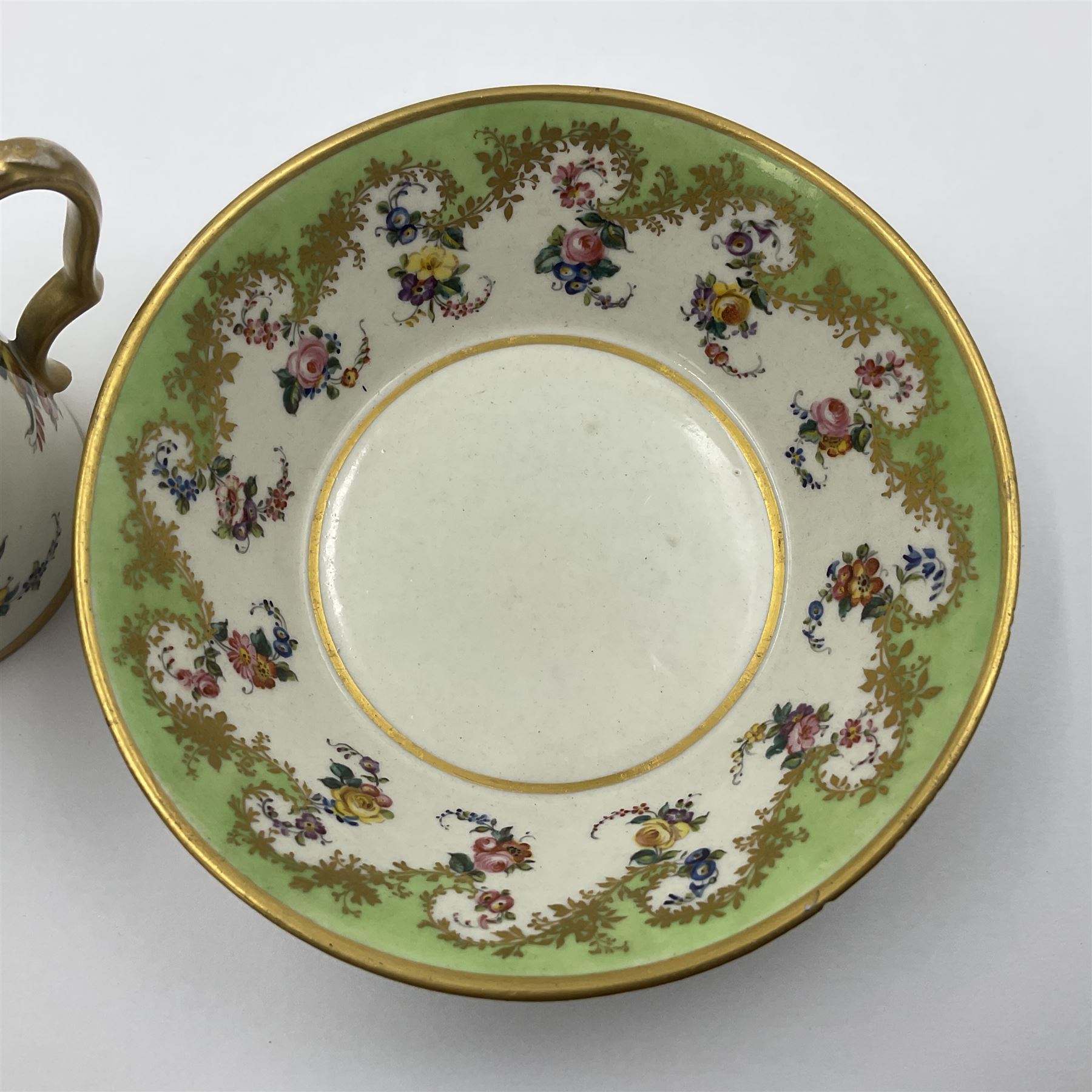 Sèvres soft paste porcelain coffee can and saucer with date code for 1754, painted and gilded with flowers, dangling from the shaped green border, interlaced LL monogram enclosing the date letter A above painters mark for Dodin, coffee can H7cm, saucer D14.5cm