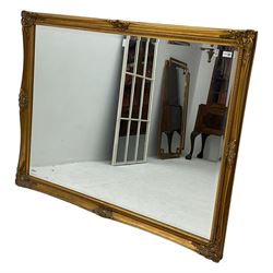 Large swept gilt-framed mirror, decorated with scrolled foliate cartouches and moulded inner slip, bevelled glass plate
