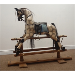  Victorian style wooden rocking horse by The Worcestershire Rocking Horse Company, named Elle, with painted and dappled carved sectional body, horsehair mane and tail, leather bridle and saddle with brass stirrups, and forward and backward action on stripped pine refectory style base W135cm H113cm  