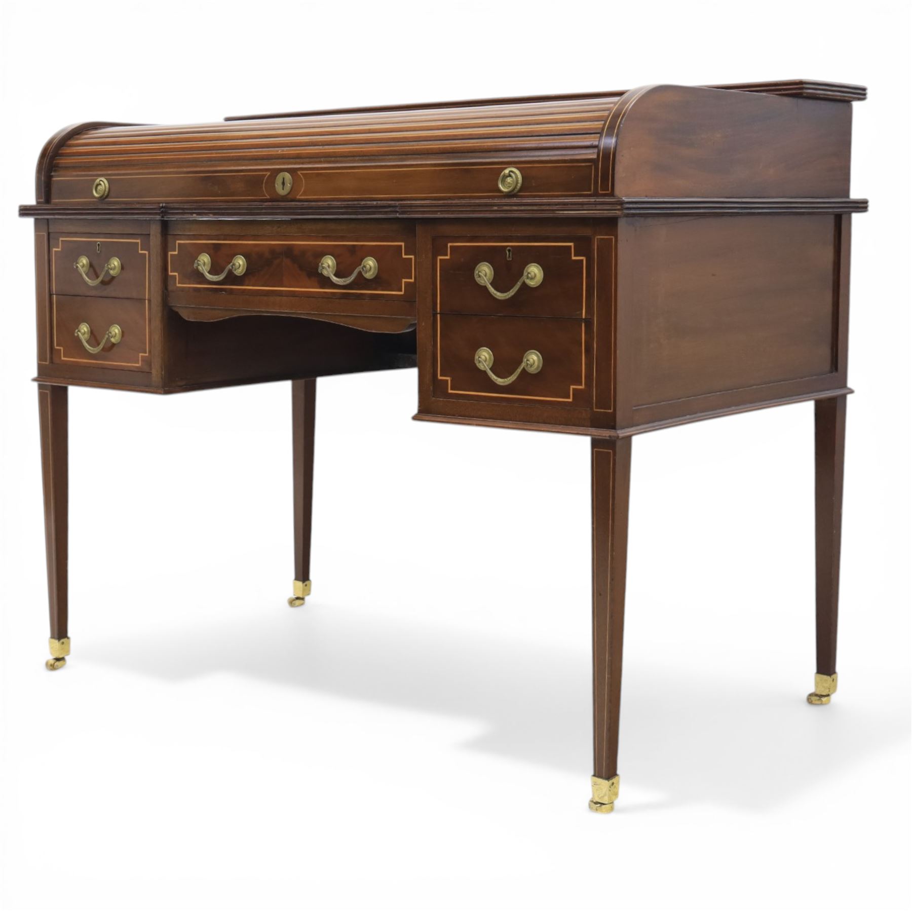 George III style inlaid mahogany tambour desk, the roll top enclosing fitted interior with small drawers and compartments above inset leather writing surface, over three frieze drawers, raised on square tapering supports with brass caps and castors