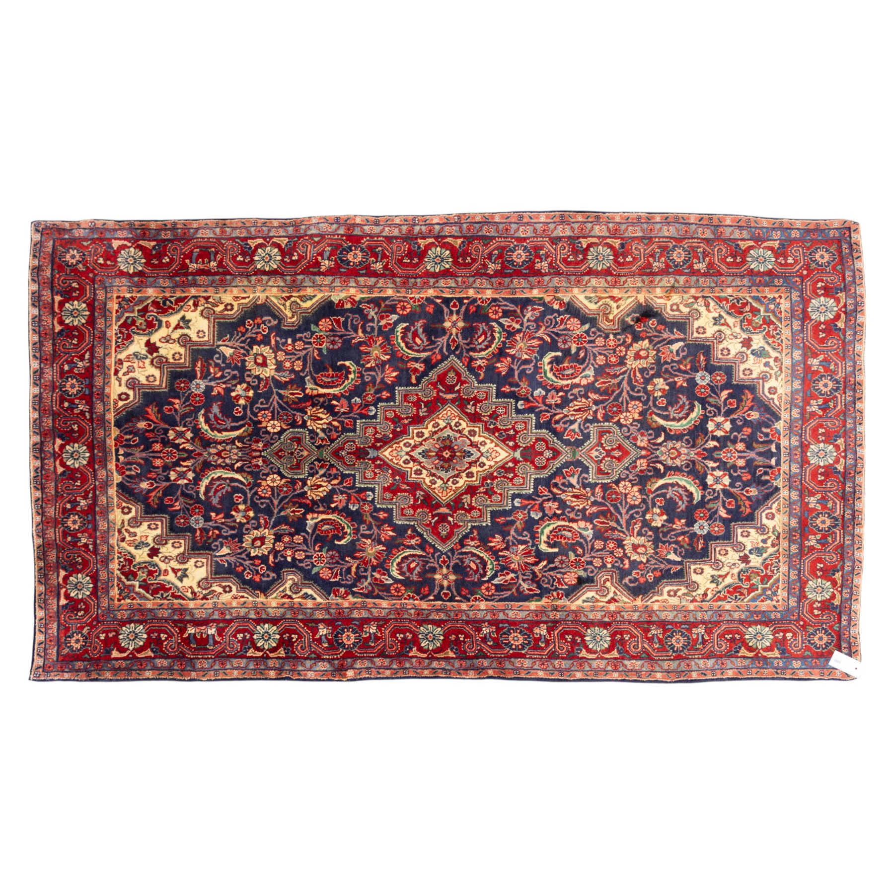 North West Persian hand-knotted Sarouk rug, central navy ground field with cusped lozenge medallion with pendant motifs, scrolling palmettes, and floral sprays, cream spandrels, and madder red border of stylized rosettes and leafy meandering vines between multiple guard stripes 