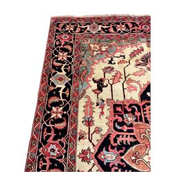 North West Persian Heriz carpet, ivory ground with large central medallion and floral spandrels, triple band border with scrolling design decorated with flower head and plant motifs 