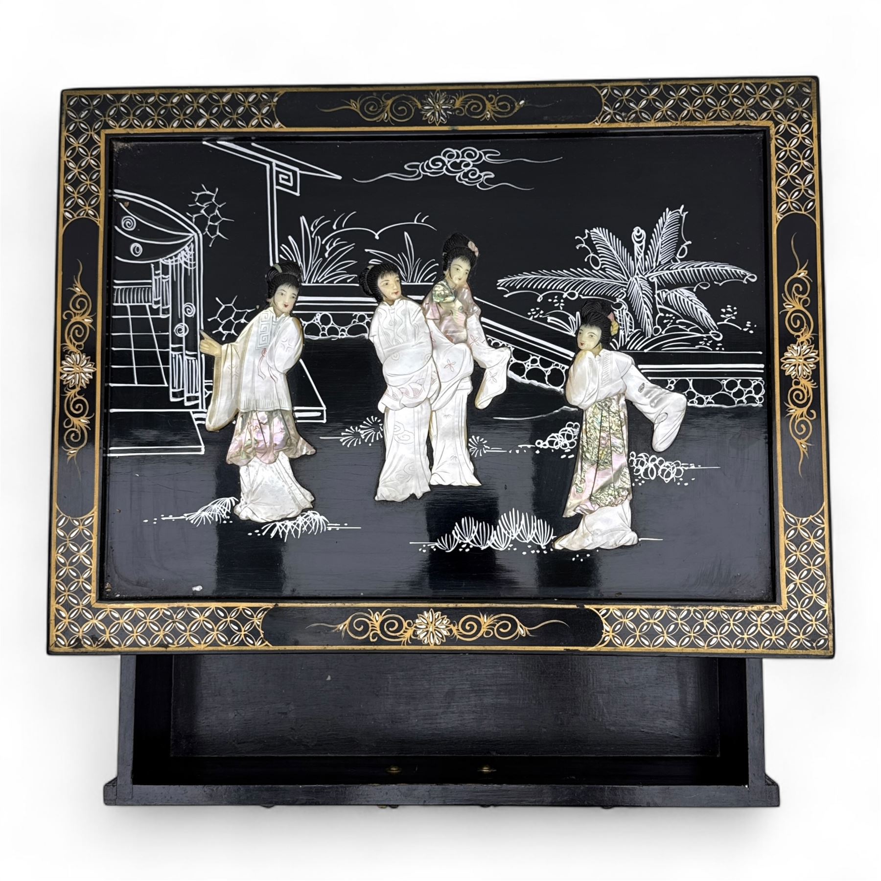 20th century Japanese Shibayama style black lacquered cabinet, rectangular form decorated with mother-of-pearl and hardstone figural inlay, the top with four standing figures, single frieze drawer above two cupboard doors, gilt painted borders and landscape