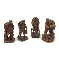 Four Chinese carved wooden figures, modelled as fishermen with their catch, one modelled with birds at his feet, with inset eyes and teeth, approximately H20cm. 
