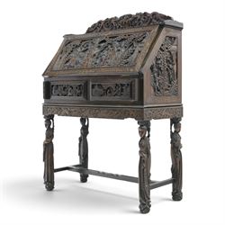 Early 20th century Chinese export carved hardwood writing bureau, the sloped fall front deeply carved with a narrative figural scene beneath pine and prunus trees, above a pair of rectangular carved panels, the shaped crest rail with entwined dragons, interior fitted with pigeonholes and a central drawer, on figural front supports with shaped stretcher