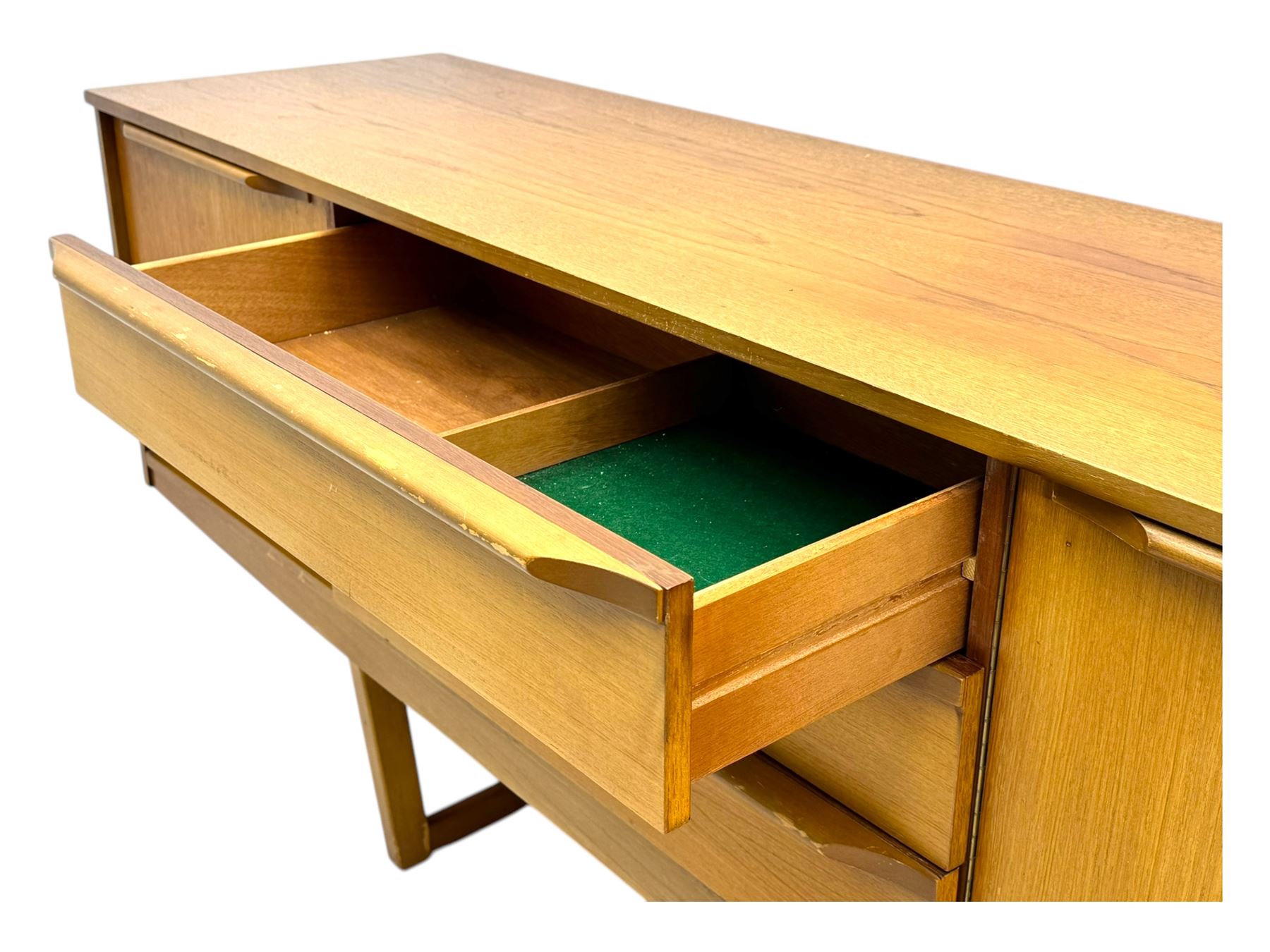 Mid-20th century teak sideboard, fitted with a fall-front cupboard, three drawers including a green baize-lined cutlery drawer, and a double cupboard, with integrated handles, on sleigh supports
