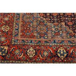 Persian indigo ground Herati rug, the busy field with a central lozenge pole medallion surrounded by repeating Herati motifs, within a shaped spandrel border the crimson guard band decorated with repeating palmette motifs