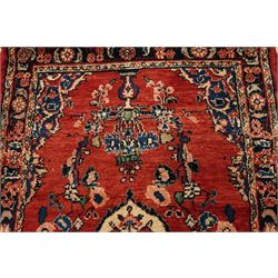 Persian Hamadan runner rug, the vermilion ground decorated with a row of ivory and indigo medallions interspersed with stylised flowering plants, indigo spandrels, enclosed by an indigo floral border and narrow patterned guard stripes