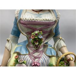 Large pair of late 19th century Continental figures in the Meissen style, modelled as a gardener and companion in 18th century dress, holding baskets of flowers and posies, each upon naturalistically modelled floral encrusted square base with scroll moulded sides, with underglaze blue cross sword type marks beneath, tallest example H49cm