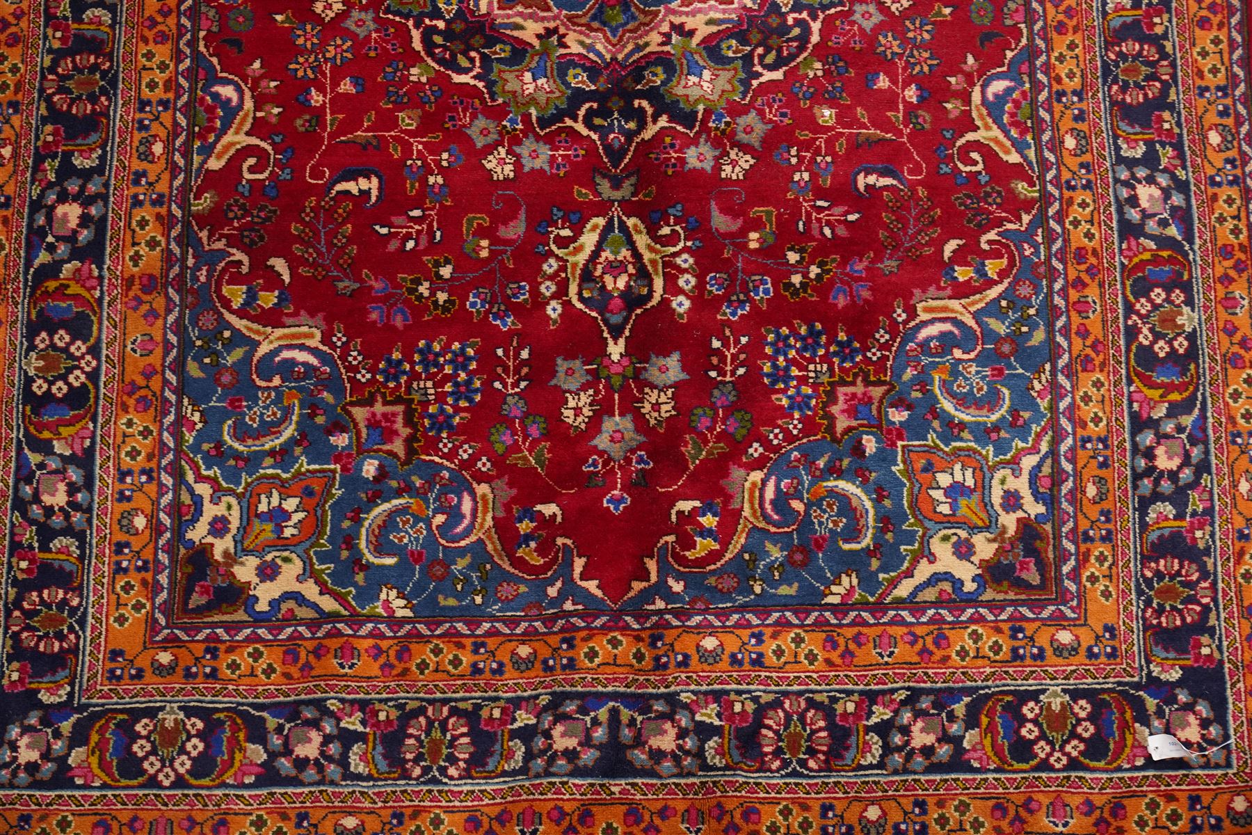 Persian Kashan hand-knotted rug, madder red ground centred by circular floral medallion with pendants, surrounded by scrolling vines, palmettes and flowerheads, dark navy spandrels, enclosed by dark navy floral border with multiple guard stripes