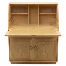 Ercol - light elm bureau, fitted with fall-front writing surface revealing adjustable shelving, above a single long drawer and twin cupboard doors, on plinth base