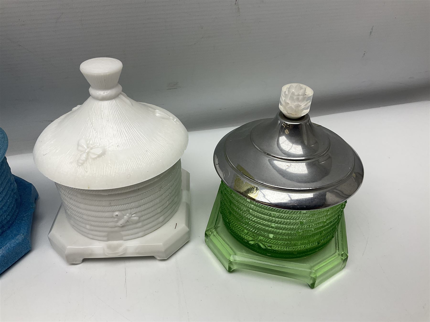 Collection of glass beehive honey pots, to include a blue slag example, milk glass, pink, green, etc together with four white metal examples (16) 