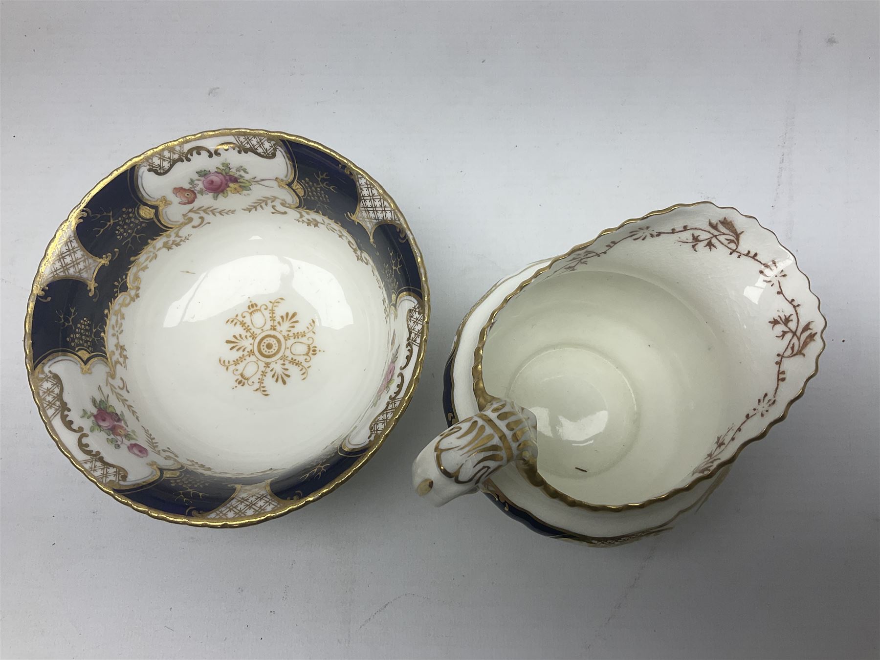 Coalport cobalt blue batwing pattern tea wares, decorated with finely enamelled floral sprays within gilt reserves, comprising teacup trio, coffee can and saucer and other cup and saucer, twin handled cake plate, milk jug and open sucrier, and circular plate retailed by T. Goode & Co London, pattern no Y2665,  all with green Coalport AD 1750 marks beneath, largest W26cm (11)