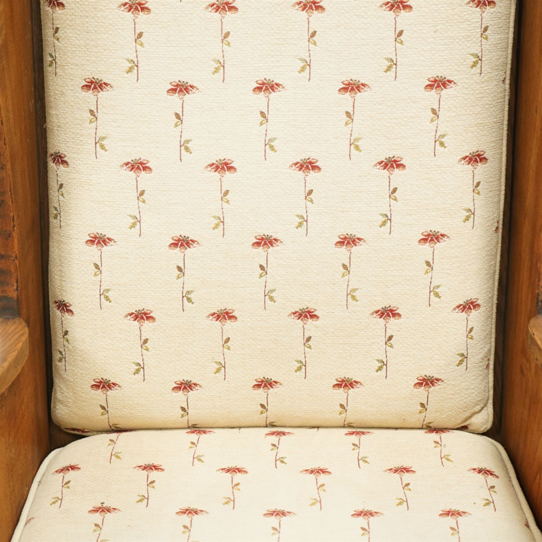 20th century pair of country lambing chairs in light oak, each with high winged back and shaped arms, pegged construction with panelled sides and arched aprons, loose seat and back cushions upholstered in cream floral fabric