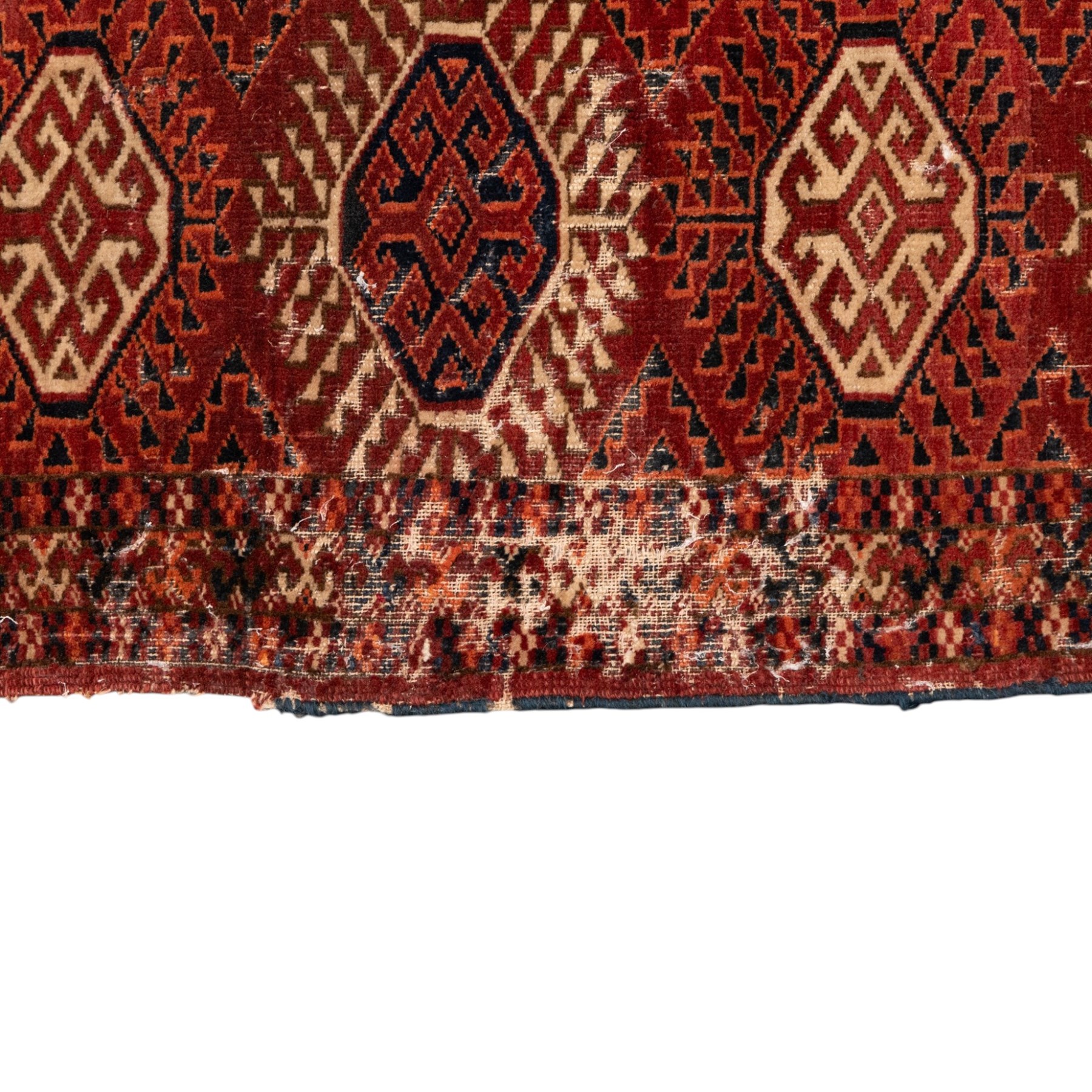 Persian Bokhara crimson ground rug, the field decorated with five rows of repeating Gul motifs with interspersed geometric design, enclosed by a guard band of further geometric-style Gul designs comprised of hook motifs