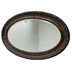 Early 20th century oval mirror, moulded frame decorated with trailing foliage and berries, bevelled plate