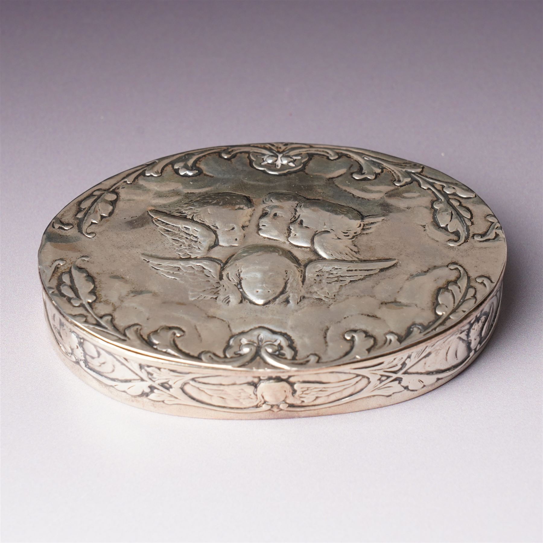 Edwardian silver oval dressing table box, the hinged cover embossed with angel heads W10cm London 1902 Maker William Comyns & Sons and an Edwardisn pierced silver oval sweetmeat basket L18cm Sheffield 1907 Maker James Dixon & Sons Ltd