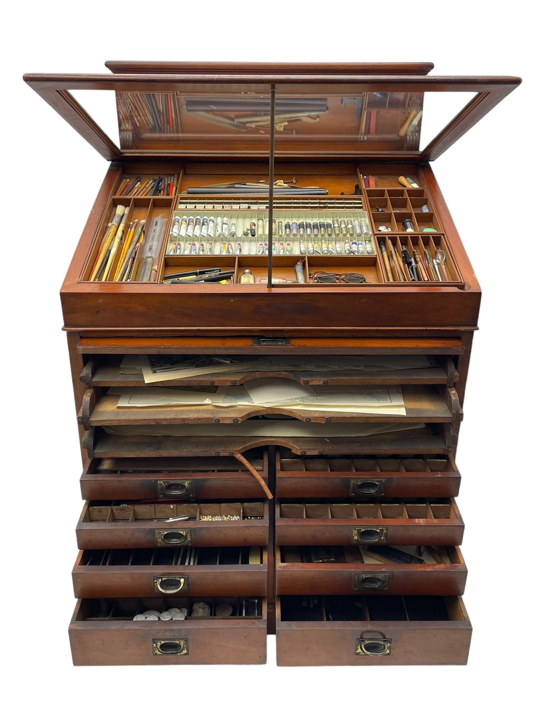 Edwardian mahogany artist's cabinet once belonging to the British artist Eli Marsden Wilson (1877-1965), raised panelled back mounted by carved brackets, sloped and hinged glazed lid enclosing paint holders and compartments, up-and-over panelled door revealing three slides, fitted with two banks of five graduating drawers with recessed brass handles, on skirted base.

Together with a quantity of artists' equipment and tools including paints, paintbrushes, charcoal, chalks, etc. and various prints relating to the life of the artist, including Quaker anti-war posters, Victorian Stevengraphs, and various chromolithographs 

Provenance: Removed from the studio of Eli Marsden Wilson. The cabinet comes to us for sale through family descent. The vendor is descendant of Marsden. Many further etchings removed from the cabinet are being sold in the Spring Art Sale, Friday 15th March 2024, Lots 265-271.

Notes: born in Ossett, Eli Marsden Wilson was the only son of Alfred Wilson, a foreman beamer, and Emma Marsden, and had five sisters. After studying at Wakefield College of Art, he moved to the Royal College of Art in London, where he became a pupil of Sir Frank Short. He had his first exhibit at the Royal Academy in 1905, the same year he married fellow artist Hilda Mary Pemberton.

A Quaker, vegetarian, and pacifist, he was a conscientious objector in World War I and as such was imprisoned in 1917 for two years. In September 1922 he was commissioned by Princess Marie Louise to produce miniature etchings for Queen Mary's Dolls' House at Windsor Castle; two such etchings are being sold in the Spring Art Sale, Friday 15th March 2024, Lot 265.