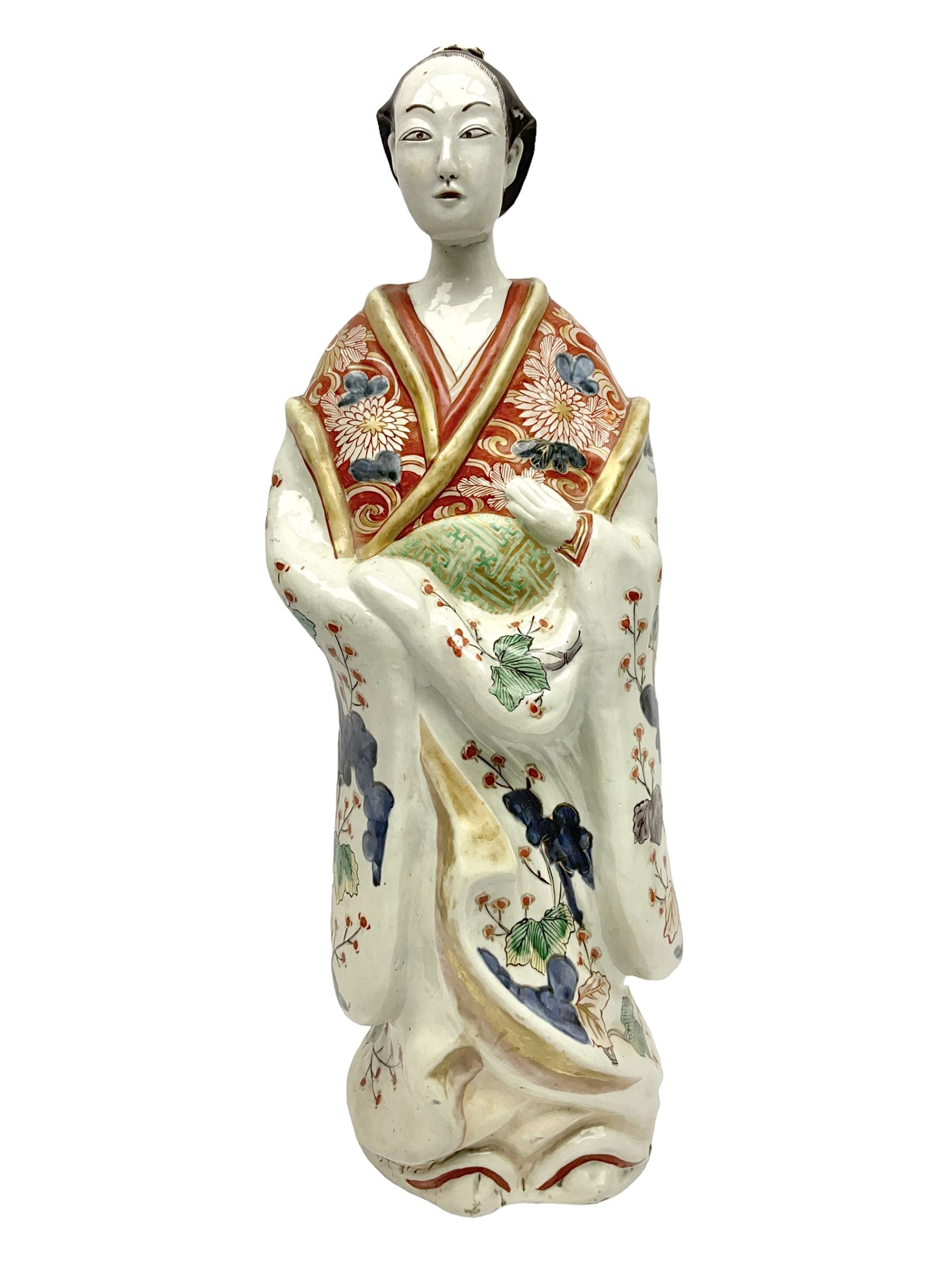Large Japanese Imari porcelain figure, modelled as a Bijin, wearing a long kimono decorated with apple blossom and leafy branches on a white ground, with gilt detailing, possibly Edo period, H63cm