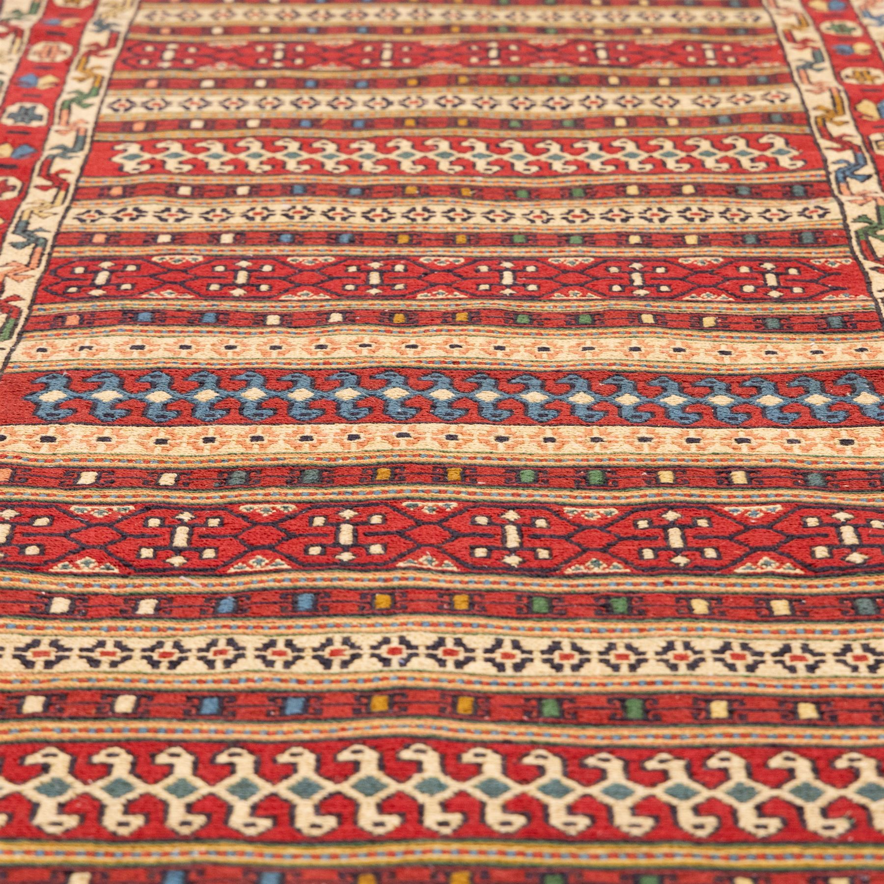 North East Persian Sumak flatweave kilim runner, elongated field decorated with horizontal bands of stylized geometric motifs in madder red, ivory, indigo green, and ochre enclosed by bold geometric borders  