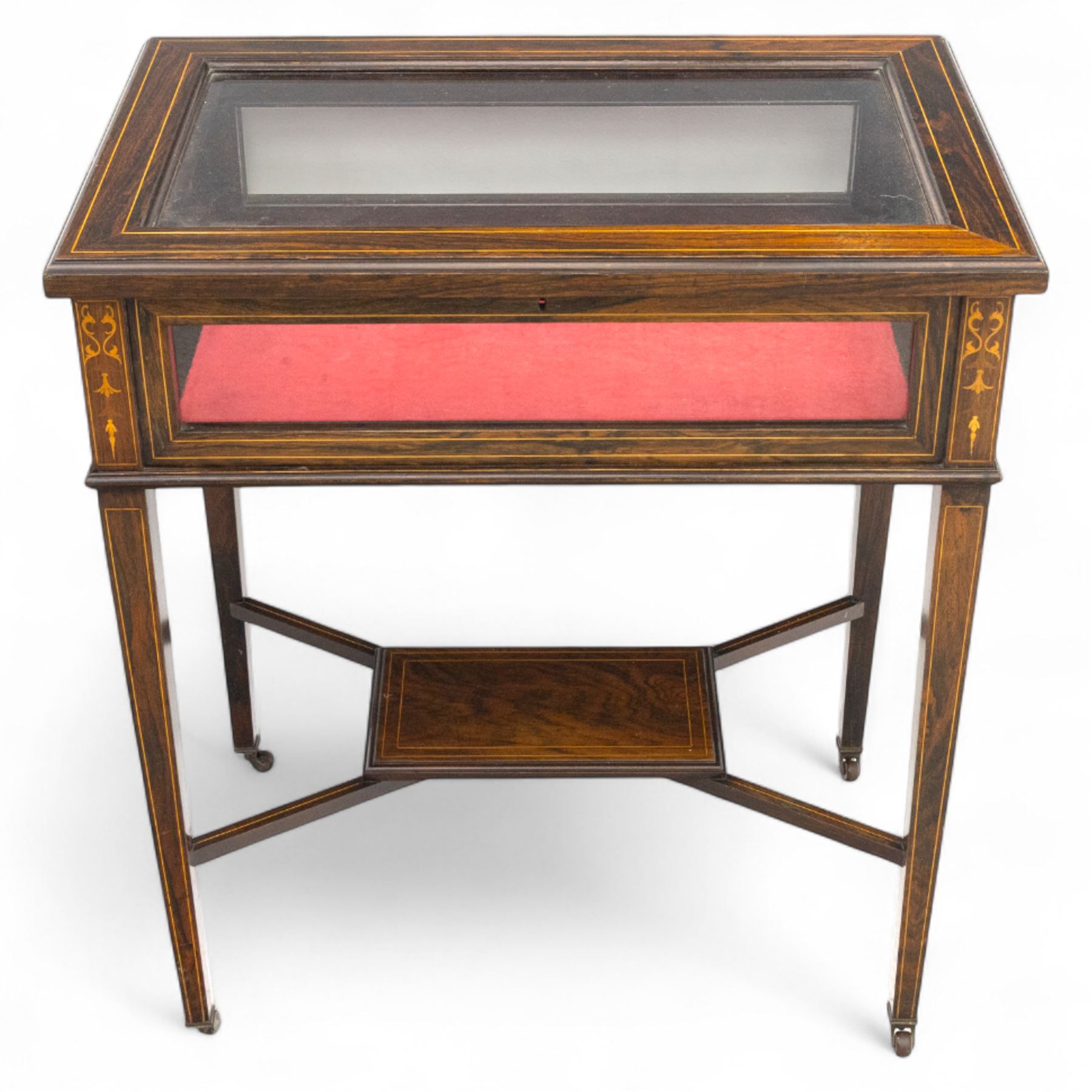 Edwardian rosewood bijouterie cabinet, the hinged rectangular top with line inlay enclosing a velvet lined interior, upon slender tapering legs inlaid with satinwood foliate marquetry decoration, with stretchers united by an under tier, raised on castors 