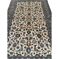 Persian Kashan ivory ground rug, decorated with interlaced leafy branches and stylised plant motifs, guarded border with scrolling design
