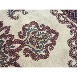Northwest Persian signed Tabriz ivory ground carpet, central medallion with intricate floral motifs, the field and spandrels decorated with scrolling tendrils and palmettes, ivory main border with crimson and indigo floral decorations, surrounded by crimson guard bands
