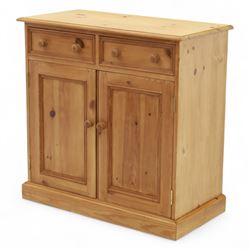 Contemporary pine storage cabinet, the rectangular top with rounded corners, over twin drawers and panelled cupboard doors, fitted with turned knob handles, plinth base
