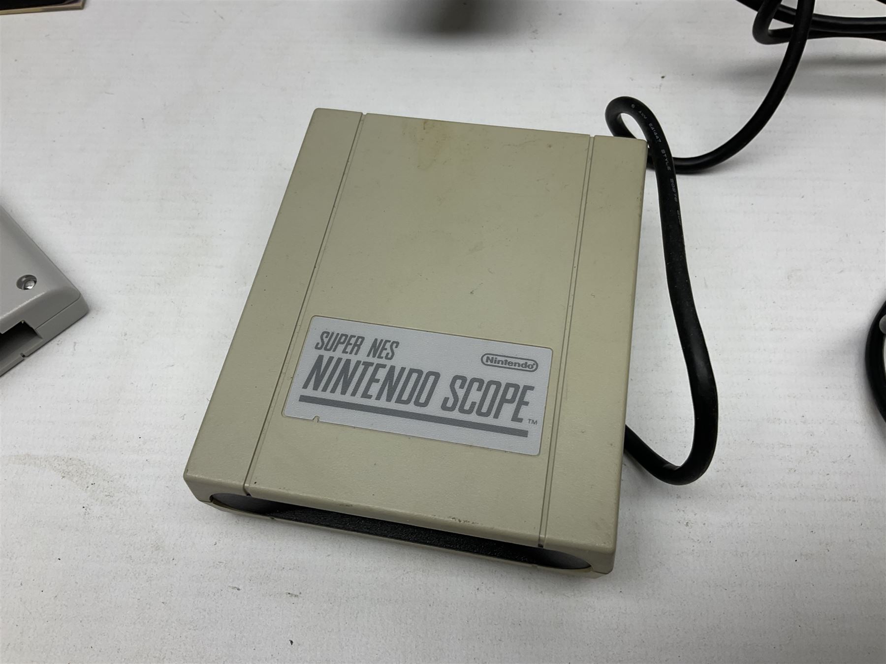 Two Super Nintendo Entertainment System (PAL) controllers, accessories and games. Super NES Game Commander with original box and instruction booklet, Super NES Nintendo Scope (1992) transmitter gun, receiver, Super NES Nintendo Scope 6 game with original instruction booklets. Further games to include ‘The Legend of Zelda a Link to the Past’, ‘Super Mario World’, ‘Super Mario Kart’, ‘The Lawnmower Man’, and ‘Exhaust Heat’, all with original instruction booklets. ‘PowerMonger’ and Disney’s ‘Aladdin’ game cartridges only 