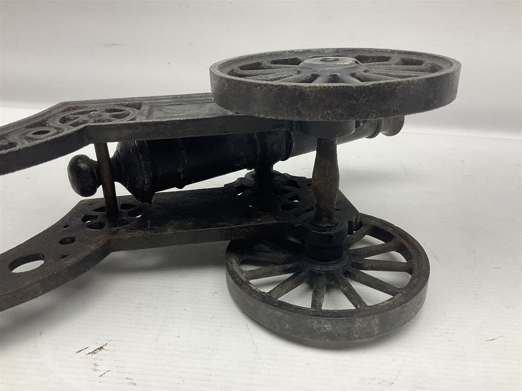 Victorian cast-iron and steel signal cannon, approximately half-inch bore, with 23cm ringed barrel and cylindrical trunnions, on a cast iron carriage with two twelve-spoked wheels and guilloche pierced swept back support, L43cm overall