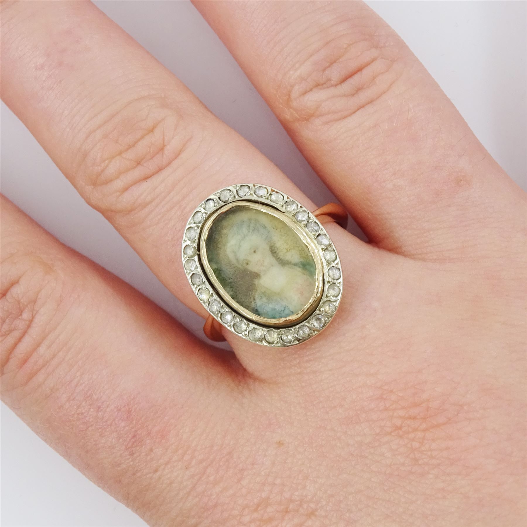 19th century 9ct gold diamond portrait ring, set with an oval miniature of a woman in 18th century dress on ivory, under a glazed panel, with rose cut diamond surround, on later shank. This lot has been registered for sale under Section 10 of the APHA Ivory Act