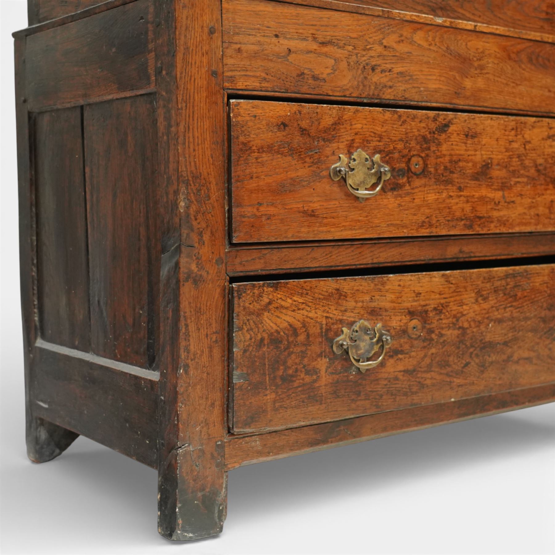 Georgian rustic oak housekeeper’s cupboard, moulded cornice above a pair of fielded panel cupboard doors enclosing a boarded interior with central divider and hanging hooks, the base fitted with two long drawers with brass swan neck handles, raised on stile supports