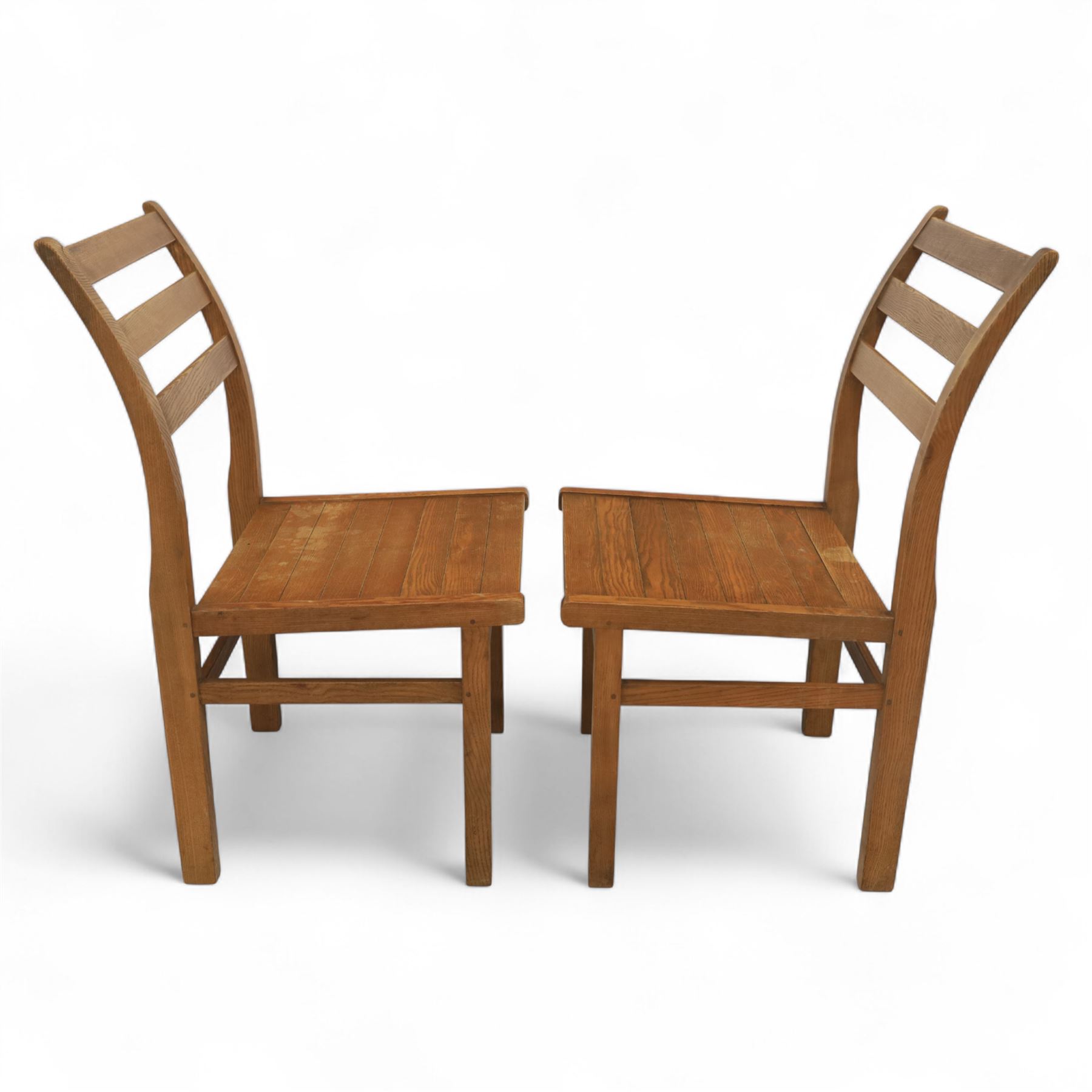 Treske of Thirsk - solid oak refectory dining suite, rectangular top with chamfered edge over trestle base united by a central stretcher, together with six matching slat back dining chairs, including two carvers, with panelled seats and square legs united by stretchers (H 87cm, W 62cm, D 57cm)