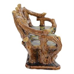 19th century pottery model of a bench, possibly Skey Pottery Tamworth, Staffordshire, the shaped seat mottled in shades of green, dark blue, yellow and brown, supported upon naturalistically modelled tree stumps, the arms and back modelled as intertwined branches, H14cm W21cm D10cm