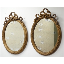  Pair 19th century gilt gesso oval mirrors, reeded frame surmounted by a ribbon tied crest, H66cm x W47cm   