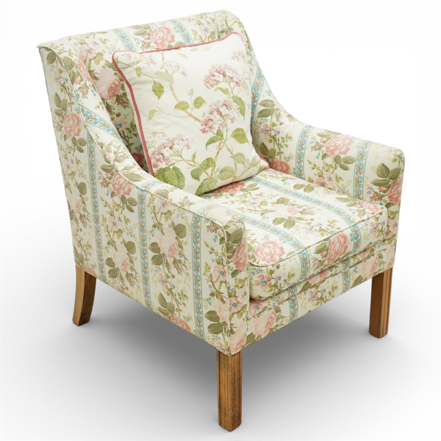 Pair of Edwardian upholstered armchairs, each with shaped padded back flanked by scroll arms, loose seat cushions, upholstered throughout in rose patterned fabric with vertical floral bands, raised on square tapering wooden legs