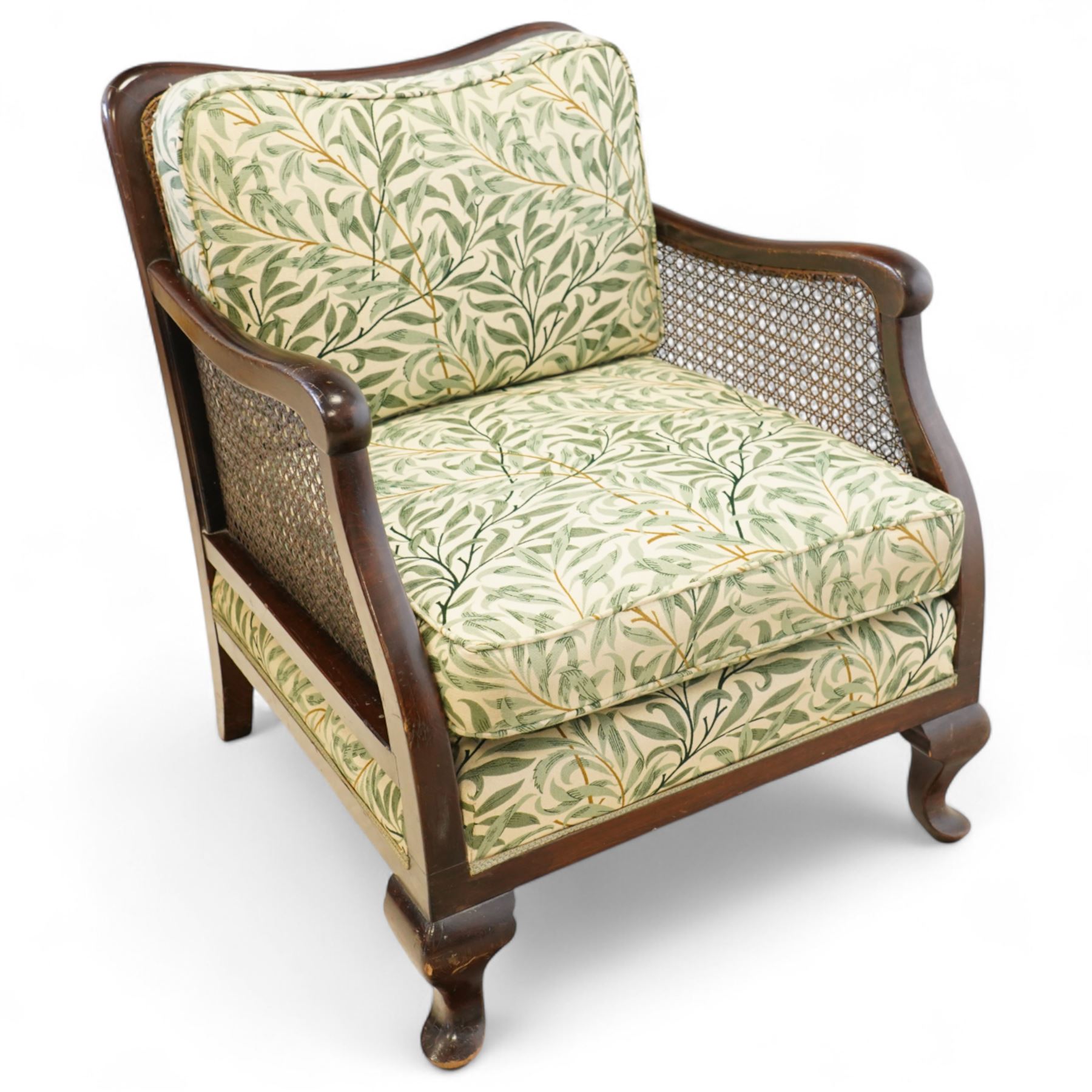 Edwardian stained beech Bergère armchair, with double cane sides and back, with the apron seat and cushion seat and back cushion, upholstered in a William Morris Willow Bough fabric, supported on cabriole legs with pad feet 