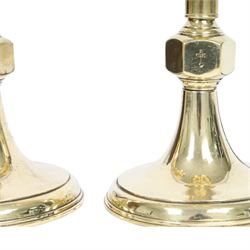 Pair of early 20th century brass alter candlesticks converted to table lamps, each with stepped and spreading circular base leading to a double hexagonal knopped column, and plain socket above inverted domed circular drip pan, the socket with light fitting, overall H49cm