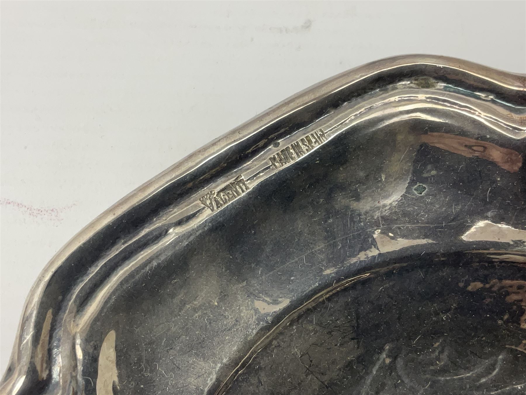 Silver plated tray, with shaped rim and embossed with a dog and crown to centre, stamped Valenti, together with three silver plated decanter labels, two port and one Bucellas, a plated cream jug with embossed floral decoration and a pair of plated fish knives engraved with double headed eagle to handle, tray W25.5