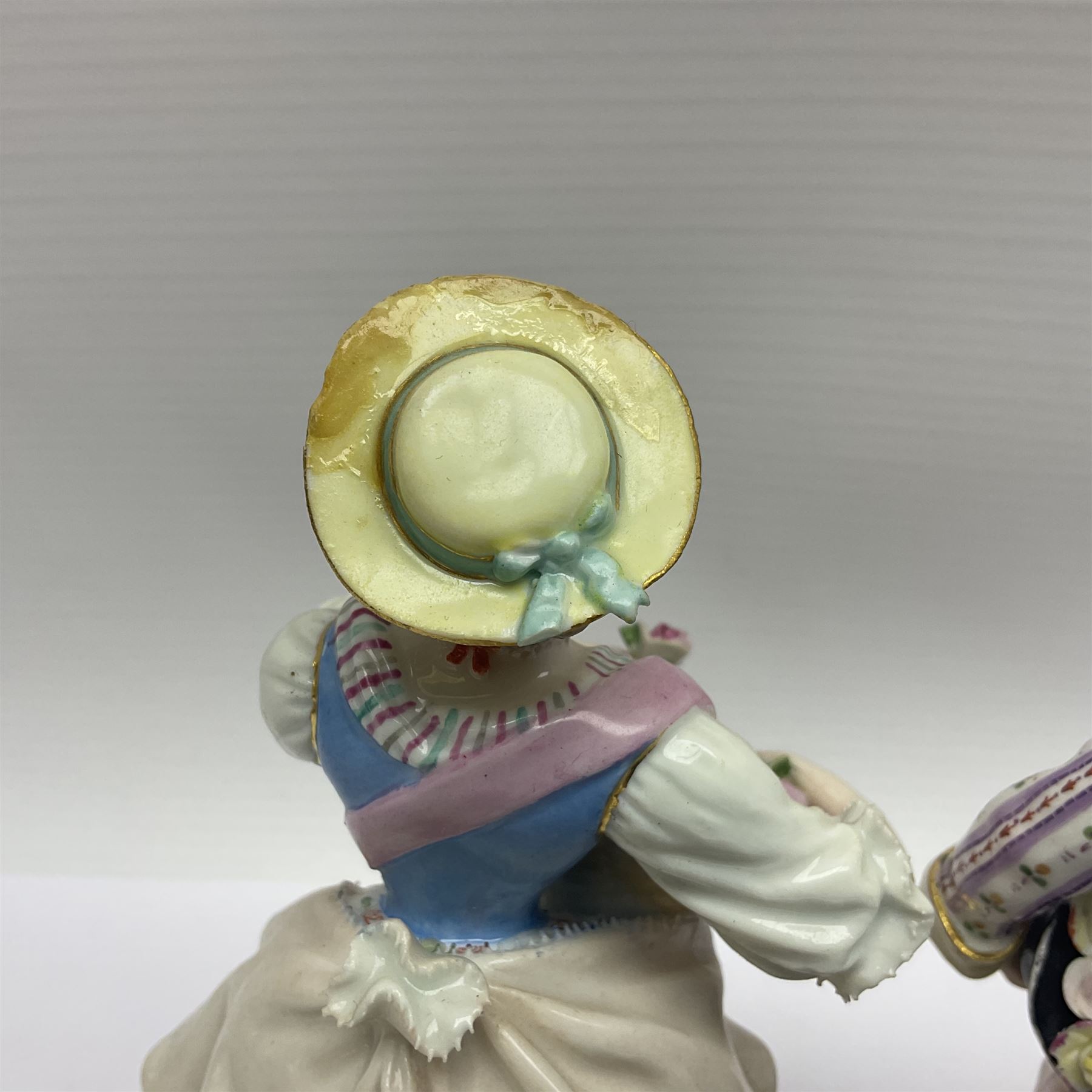 Pair of late 19th/early 20th Century Meissen figures, modelled as flower sellers, after the original by Michel Victor Acier, she holding basket of flowers, he holding flowers in his hat, each with underglaze cross swords mark beneath, tallest H16.5cm