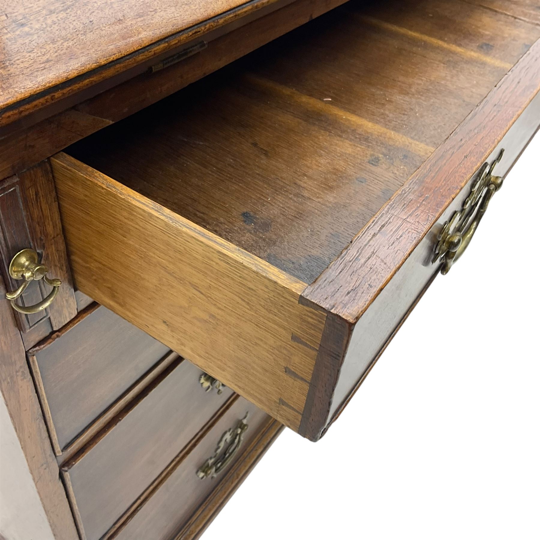 George III mahogany bureau, fall-front enclosing a fitted interior of drawers, pigeonholes and central mirrored cupboard, over four graduated cockbeaded drawers with brass batwing handles, raised on bracket feet